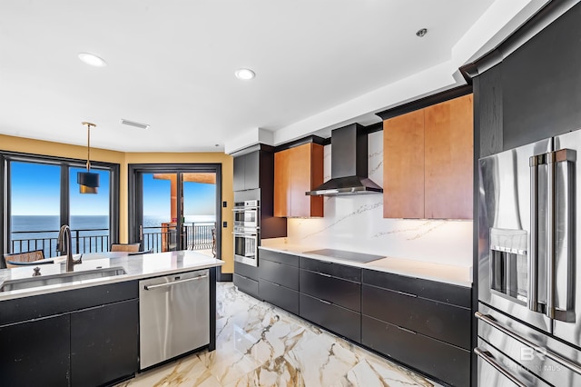 kitchen featuring a sink, marble finish floor, appliances with stainless steel finishes, dark cabinetry, and wall chimney exhaust hood