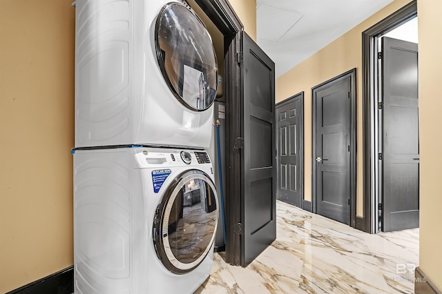 washroom featuring marble finish floor, laundry area, and stacked washer and clothes dryer