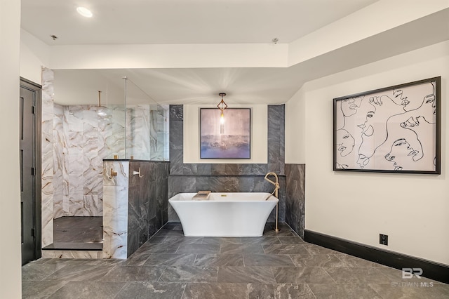 full bath featuring marble finish floor, a soaking tub, a marble finish shower, and tile walls