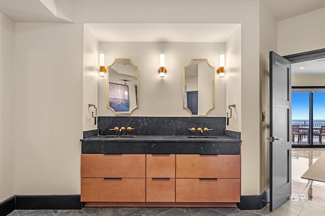 full bath with a sink, baseboards, and double vanity