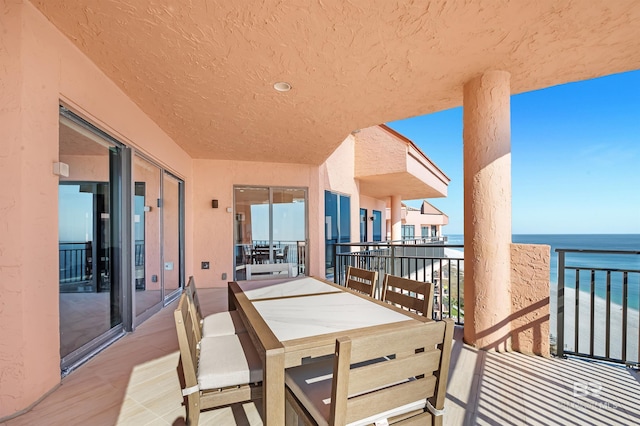 balcony featuring outdoor dining space and a water view