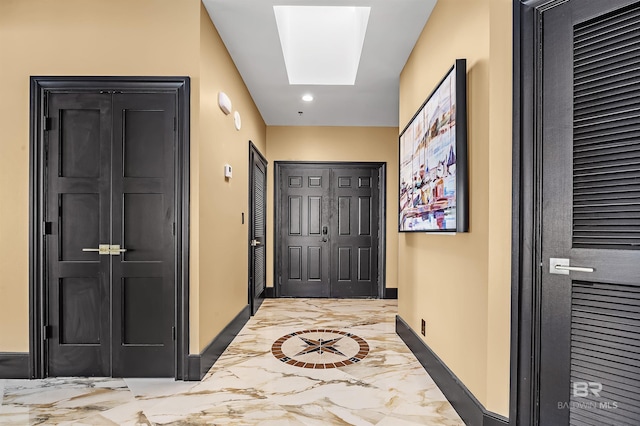 doorway to outside with marble finish floor, recessed lighting, a skylight, and baseboards