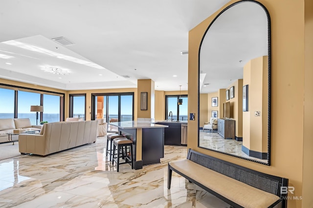 kitchen featuring a breakfast bar, marble finish floor, open floor plan, a kitchen island, and a sink