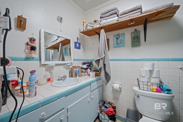 bathroom featuring crown molding, vanity, toilet, and tile walls