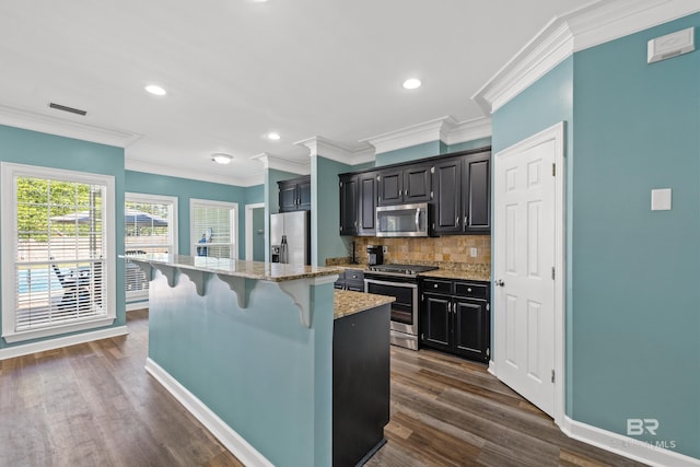 19083 County Road 13, Fairhope, AL 36532 - kitchen featuring appliances with stainless steel finishes, a breakfast bar area, decorative backsplash, a kitchen island, and dark cabinets