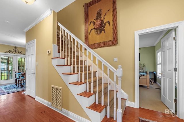 stairs with hardwood / wood-style flooring and crown molding