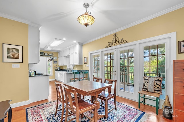 dining room with french doors, light hardwood / wood-style flooring, and crown molding