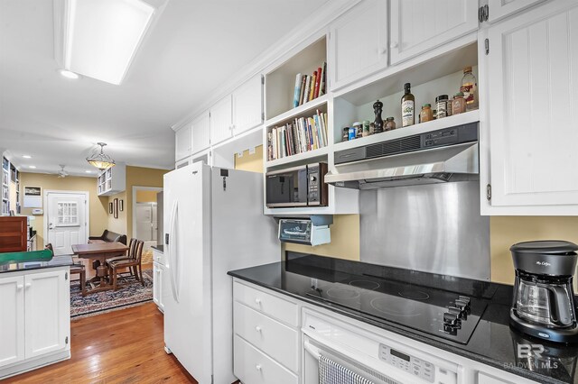 kitchen featuring black microwave, ventilation hood, white cabinetry, white fridge with ice dispenser, and light hardwood / wood-style floors