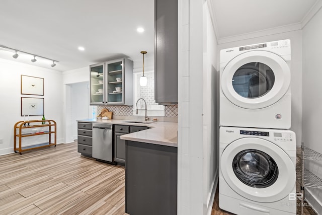 laundry area featuring sink, ornamental molding, stacked washer and clothes dryer, and light hardwood / wood-style flooring