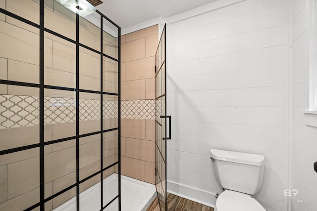 bathroom with a tile shower, hardwood / wood-style floors, and toilet