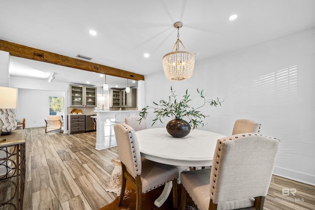 dining area with a chandelier, light hardwood / wood-style flooring, and beamed ceiling