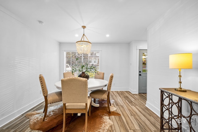 dining area with a notable chandelier, light hardwood / wood-style floors, and crown molding