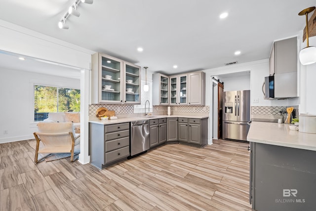 kitchen featuring gray cabinetry, pendant lighting, sink, decorative backsplash, and appliances with stainless steel finishes