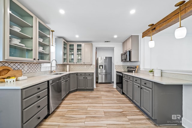 kitchen featuring sink, hanging light fixtures, backsplash, gray cabinets, and appliances with stainless steel finishes