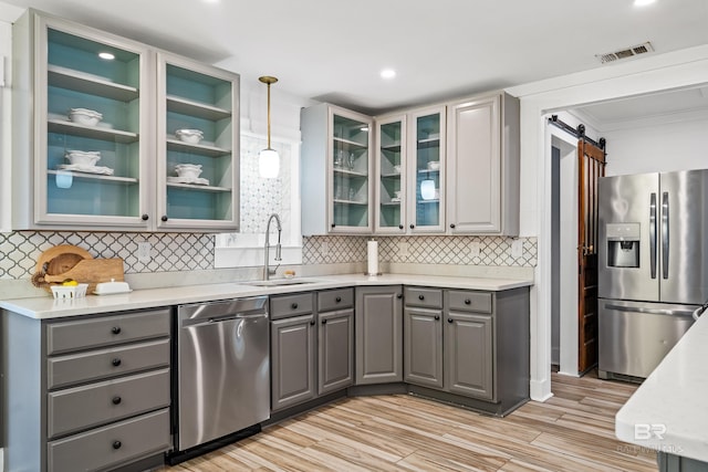 kitchen with a barn door, sink, gray cabinets, and appliances with stainless steel finishes