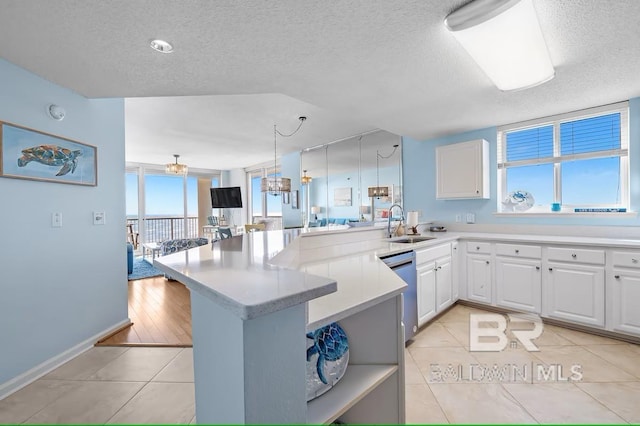527 Beach Club Trl Unit D710, Gulf Shores, AL 36542 - kitchen with stainless steel dishwasher, a peninsula, a sink, light tile patterned flooring, and a textured ceiling