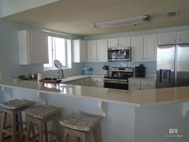 527 Beach Club Trl Unit D710, Gulf Shores, AL 36542 - kitchen featuring appliances with stainless steel finishes, a peninsula, a textured ceiling, and white cabinetry