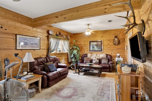 living area with wood walls, a ceiling fan, and beamed ceiling