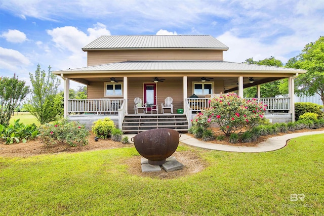 farmhouse-style home featuring a ceiling fan, a front lawn, a porch, and metal roof