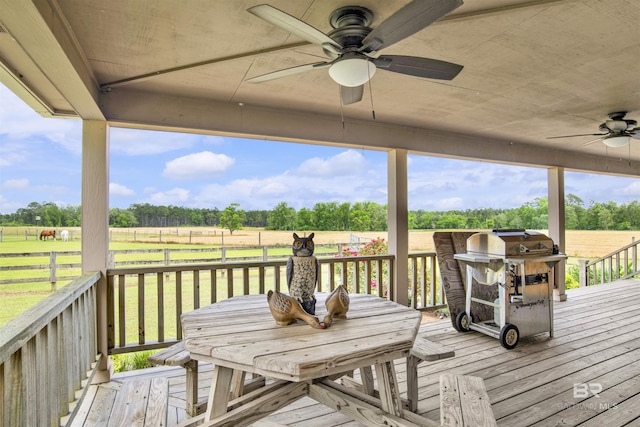 wooden terrace with ceiling fan, area for grilling, a yard, a view of countryside, and view of wooded area