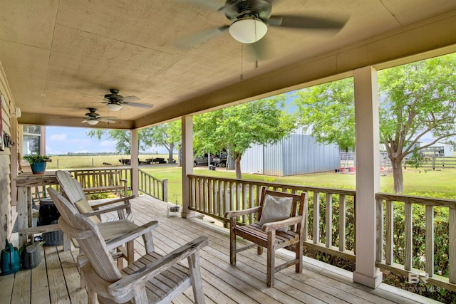 wooden deck with a ceiling fan, a yard, and a porch