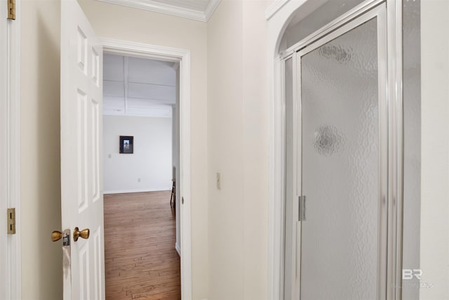 hallway featuring wood finished floors, baseboards, and ornamental molding