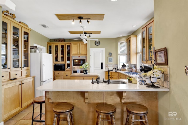 kitchen with freestanding refrigerator, a peninsula, a sink, a breakfast bar, and recessed lighting