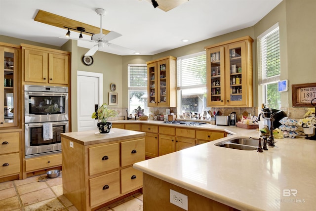 kitchen featuring appliances with stainless steel finishes, light brown cabinetry, a sink, and ceiling fan