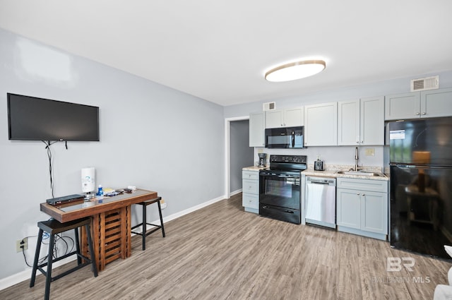 kitchen featuring sink, light hardwood / wood-style floors, and black appliances