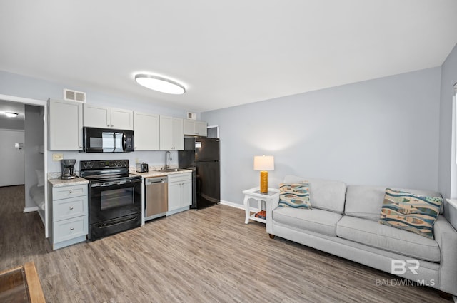 kitchen featuring white cabinetry, hardwood / wood-style floors, black appliances, and sink