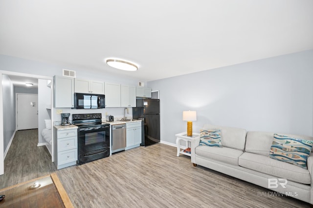 kitchen featuring white cabinetry, sink, hardwood / wood-style flooring, and black appliances