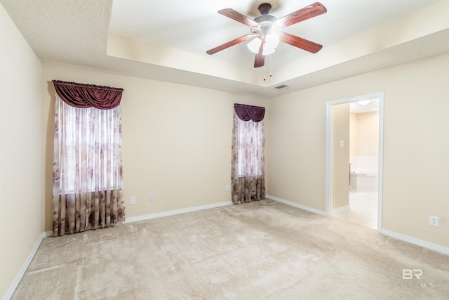 carpeted spare room featuring a textured ceiling, a raised ceiling, and ceiling fan