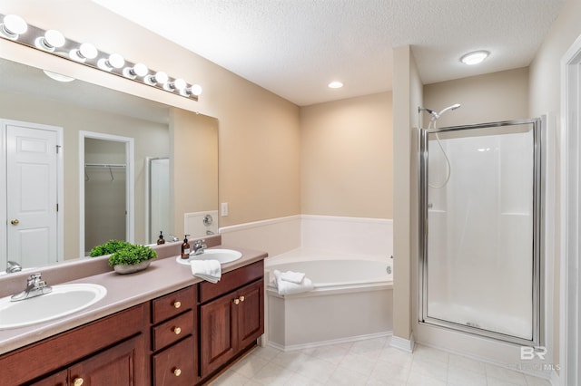 bathroom featuring a textured ceiling, vanity, and plus walk in shower