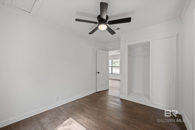 unfurnished bedroom with ceiling fan, a closet, crown molding, and dark wood-type flooring