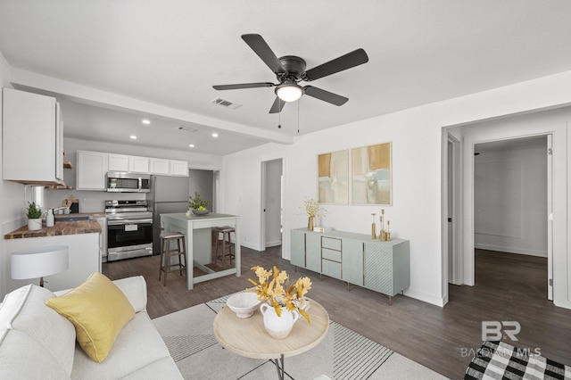 living room featuring ceiling fan, sink, and dark hardwood / wood-style flooring