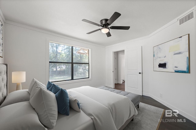 bedroom featuring ceiling fan, ornamental molding, and dark wood-type flooring