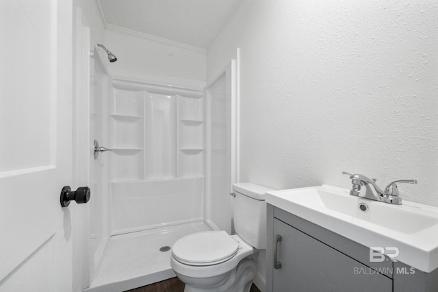 bathroom with a shower, crown molding, vanity, and toilet