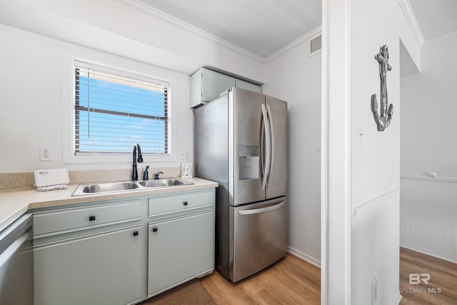 kitchen with ornamental molding, appliances with stainless steel finishes, light wood-style flooring, and a sink