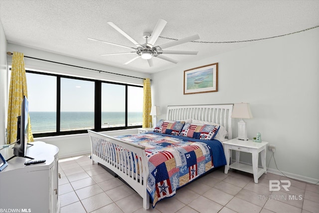 bedroom with light tile patterned floors, a ceiling fan, baseboards, and a textured ceiling
