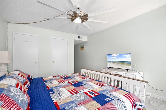 bedroom with a ceiling fan, baseboards, visible vents, a textured ceiling, and tile patterned floors