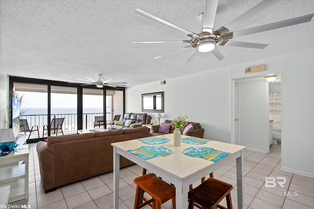 dining space with expansive windows, a textured ceiling, light tile patterned flooring, and a ceiling fan