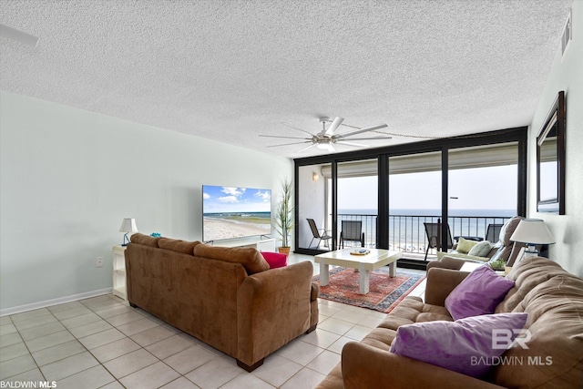 living room featuring expansive windows, a textured ceiling, light tile patterned flooring, and a ceiling fan