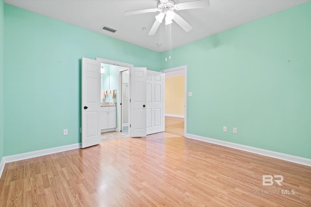 unfurnished bedroom with ceiling fan, ensuite bath, and light wood-type flooring