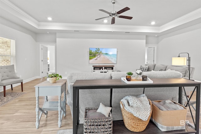 living room with ornamental molding, light hardwood / wood-style floors, a raised ceiling, and ceiling fan