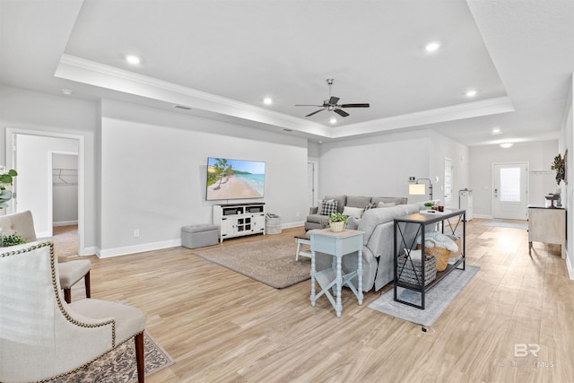 living room with light hardwood / wood-style floors and a raised ceiling