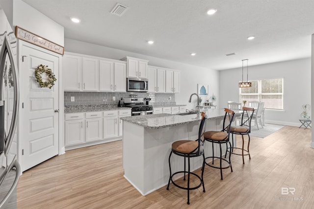 kitchen featuring white cabinetry, appliances with stainless steel finishes, decorative light fixtures, and sink