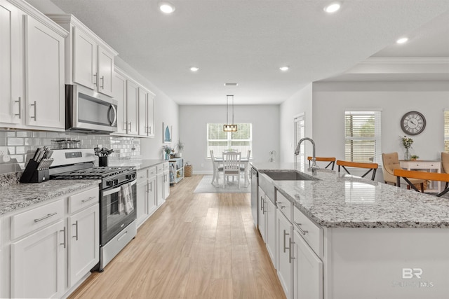 kitchen with a kitchen island with sink, white cabinetry, and stainless steel appliances