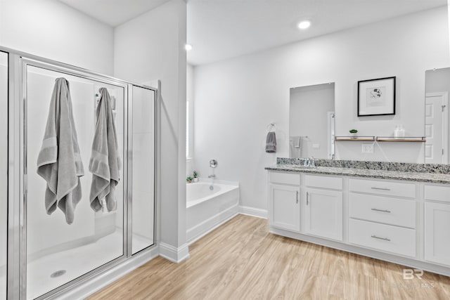 bathroom featuring vanity, hardwood / wood-style flooring, and plus walk in shower