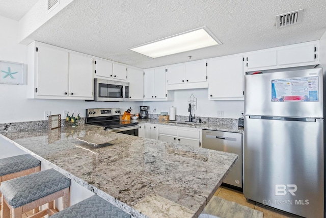 24400 Perdido Beach Blvd Unit 501, Orange Beach, AL 36561 - kitchen featuring a sink, a peninsula, stainless steel appliances, visible vents, and white cabinets