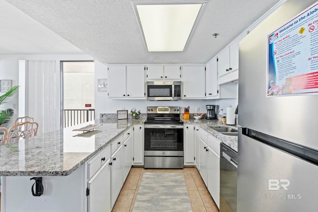 24400 Perdido Beach Blvd Unit 501, Orange Beach, AL 36561 - kitchen with white cabinets, a peninsula, appliances with stainless steel finishes, and light stone countertops